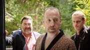 Die Geldeintreiber Cheffe (Heiko Pinkowski, l.) und Tschako (Jakob Geßner, r.) statten Müller-Weichard (Stefan Leonhard, M.) einen Besuch ab.