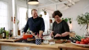 Björn Freitag (l) und Orkide Tançgil beim Kochen, Orkide schneidet Petersilie.