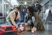 Niklas (Roy Peter Link, l.) eilt mit einem RTW sogleich zum Flughafen und trifft dort auf Vivi (Jane Chirwa, r.) und die ohnmächtige Julia (Mirka Pigulla, M. mit Komparsen h.).