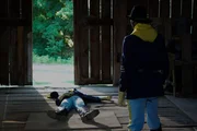 Ein Soldat steht und schaut auf den regungslosen Körper eines anderen Soldaten, der auf dem Boden liegt