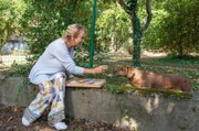 Mechthild (Diana Körner) nähert sich Nachbarshund Caesar mit einem Leckerli.