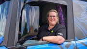 Tina sitzt im Truck, schaut aus dem Fenster, streckt die Ellbogen aus dem Fenster und lächelt.