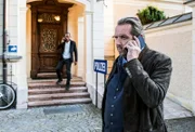 Benedikt Beissl (Andreas Giebel) und Jerry Paulsen (Peter Marton) telefonieren vor der Polizeistation.