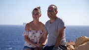 Melissa Shafrir (L) and Avi Shafrir (R) sitting on the rocks with a beautiful view of the Mediterranean Sea, during their big interview about the reasons why they moved to Mellieha, Malta, as seen on Mediterranean Life