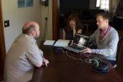 Amy Bruni is sitting next to Adam Berry as he shows homeowner Jason Brown the evidence.