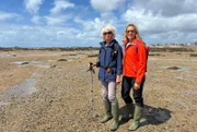 Tamina Kallert (r) wandert mit der Geografin und Wanderführerin Trudie Hairon-Trox bei Ebbe durch die Königliche Bucht von Grouville.