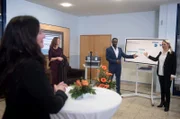 Als Britta (Jelena Mitschke, r.) droht, eine wichtige Rede in den Sand zu setzen, ist Hendrik (Jerry Kwarteng, M.) an ihrer Seite, und sie brillieren als Team. Carla (Maria Fuchs, 2.v.l.) und die Staatssekretärin (Kirsten Meier, l.) sind beeindruckt.