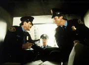 Lee (Bruce Boxleitner, r.) beteiligt sich an einem Raubüberfall auf einen Geldtransporter des Geheimdienstes. Seine Komplizen sind die gescheiterten Geheimdienstagenten Brackin (John Beck, l.) und Harris (George McDaniel, M.).