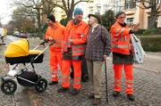 ARD Degeto DIE DREI VON DER MÜLLABFUHR - BABY AN BORD, während Tarik (Daniel Rodic, li.) sich um Findelkind Lea kümmert, helfen „Käpt’n“ Werner (Uwe Ochsenknecht) und Ralle (Jörn Hentschel, re.) einer Rentnerin (Henriette Gonnermann).