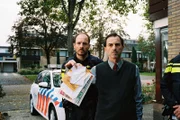 Der Nachbar (René van ’t Hof) zeigt die Post, über die Kees gepinkelt hat. Der Polizist (Huub Smit) steht hinter ihm.