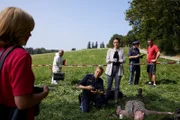 Polizeihauptmeister Mohr (Max Müller, M.) und Pathologin Mai (Sina Wilke, r.) schildern Kommissarin Danner (Katharina Abt, l.) den vermeintlichen Tathergang. (Im Hintergrund: Komparsen).