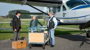 Swantje (Nadine Boske) und Hauke (Jan-Gregor Kremp) checken das ungewöhnliche Fluggepäck des Passagiers Ralf Klingenberg (Oliver Törner, li.) ein.