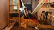 After completing her tiny house, builder, Sophie Clark, takes a moment to relax with a book in her hammock, with her faithful companion Whisky at her feet, in Seattle, Washington, as seen on Tiny House, Big Living.