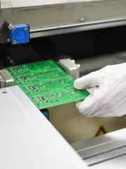 Electronic factory worker holding assembled PCB with SMT also called Surface Mount Equipment. Image taken at Electronics manufacturing plant and the PCB board assembled with electronic components.