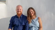Katherine Sinclair (R) and Lowell Kitchen (L) sitting outdoors during a sunny, windy day in Paros, Greece, as seen on Mediterranean Life