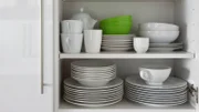 white crockery stacked in cupboard with green bowl