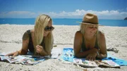 Women are lying on the beach.