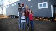 The Johnson family poses in front of their house smiling at the camera, for Ty and Taylor's build, in Enid, Oklahoma, as seen on Tiny House, Big Living.
