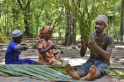 Mit Dula flechten Awena und Abduli einen Erntekorb aus einem Palmwedel.