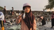 Nina hält einen toten Fisch in der Hand, den sie bei einer Müllsammelaktion mit ihrer Pfadfindergruppe gefunden hat.