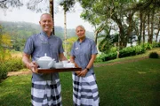 Die Moderatoren Rob Rinder und Monica Galetti servieren Tee in den Butler-Uniformen im Hotel Ceylon Tea Trails in Sri Lanka.