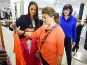 Lala (M.) ist zusammen mit Shoppingbegleitung Tatjana (r.) auf der Suche nach dem perfekten Outfit. Eine Verkäuferin berät sie.