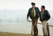 Hubert (Christian Tramitz, re.) und Staller (Helmfried von Lüttichau) suchen Bauer Weidinger auf dem Feld, da sie diesen wegen „Beihilfe zum Mord“ festnehmen wollen.