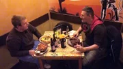 Jean (li.) hat das Fahrradrennen gegen Carsten verloren und lädt ihn nun zum Essen ein.