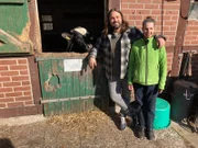 Achim Sam steht mit Bäuerin Heike an einem Kuhstall.