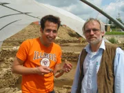 Willi Weitzel präsentiert mit dem Grabungsleiter Dr. Claus-Michael Hüssen ein Fundstück. Heute ist er dabei, wie Archäologen ein römisches Hofgut ausgraben.