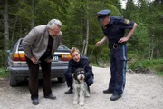 Nachdem der Trüffelhund des Verstorbenen herrenlos durch den Wald gelaufen ist, nehmen sich Kommissar Stadler (Dieter Fischer, l.), Polizeihauptmeister Mohr (Max Müller, m.) und dessen Kollege seiner an.