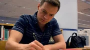Adam Berry takes notes during a research scene.