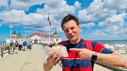 André Gatzke isst ein Fischbrötchen auf der Seebrücke.