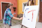 Checker Tobi beim Malen auf eine Leinwand.