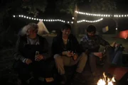 Malte (Daniel Zillmann, l.), Lars (Sebastian Schwarz, M.) und Jannos (Jasin Challah, r.) führen beschwipste Männergespräche am Lagerfeuer.