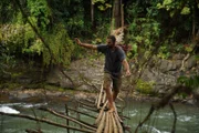 Hazen schreitet vorsichtig über eine prekäre Bambusbrücke über einen schnell fließenden Fluss mitten im Dschungel.