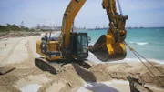 Luke Purdy and his co-workers use a dredger to dig the vessel free on the beach.