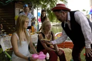 Cleos Dad (Alan David Lee) hat eine Geburtstagsparty für Cleo organisiert. Er scheint nur leider vergessen zu haben, dass seine Tochter nicht sechs sondern sechzehn wird. Verkleidet im Cowboykostüm versucht er zumindest Emma (links, Claire Holt) und Rikki (Mitte, Cariba Heine) zu begeistern.