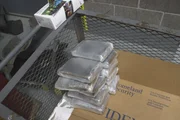 Mehrere Pakete mit mutmaßlichen Betäubungsmitteln werden in einen Wagen gelegt, nachdem sie aus dem Kofferraum des Fahrzeugs eines Verdächtigen geholt wurden, wo sie von der CBP in San Diego, Kalifornien, entdeckt wurden (National Geographic for Disney).