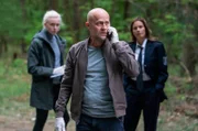 Robert Heffler (Jürgen Vogel, M.) teilt seinem Kollegen Simon am Telefon mit, dass die neue Kollegin früher als gedacht ihren Dienst antreten wird. Katharina Koblinski (Elisabeth Baulitz, r.) und Veronika Schäfer (Anne Müller, l.) beobachten die Situation aus dem Hintergrund.