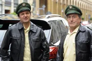 Kneidl (Winfried Frey, links) und Müller (Johann Schuler) warten auf den Besitzer des Wagens, der auf den Trambahnschienen geparkt ist.