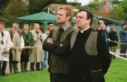 Reverend Anthony Gant (Richard McCabe, r.) muss sich zu Pferd gegen eine Schar Frauen behaupten - so will es die Tradition dieses Dorffestes. Roland Marwood (Joseph Kennedy, l.) wird ihm die Daumen drücken.