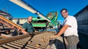 Jonas und Ronny stehen an einem Fließband der Kartoffelsortierstrecke.