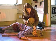 Als Elena Eichhorn (Cheryl Shepard) Tanja Wassmut (Victoria Deutschmann, liegend) in ihrem Fotolabor besuchen will, liegt sie bewusstlos auf dem Boden.