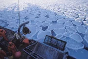 Man preparing to catch crabs on ocean with broken frozen ice on top.