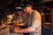 Ein U-Boot-Kommandant und zwei Offiziere berechnen den Kurs.
