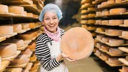Marina präsentiert einen gereiften Käselaib.