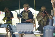 Investigator along with his team and military personnel study pieces of wreckage in the crash site tent.