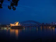 Blick auf das Opernhaus von Sydney, im Hintergrund die Harbour Bridge, am frühen Morgen.