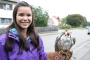 Anna mit Lannerfalke Jessie. Der Greifvogel trägt eine Falkenhaube.